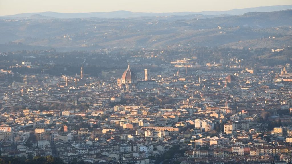 Panoramic view of Florence's historic skyline with the Tuscan countryside in the background.
